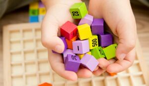 Hands holding wooden cubes with numbers