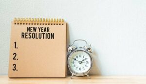 New year resolution on a notepad and alarm clock on wood table