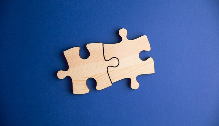 Partnership concept with two pieces of wood jigsaw puzzle on a blue background