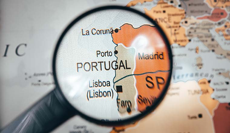 Portugal country map in focus on world map through a black color magnify glass