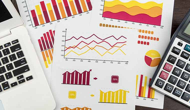 Reporting graphs, laptop and calculator on desk