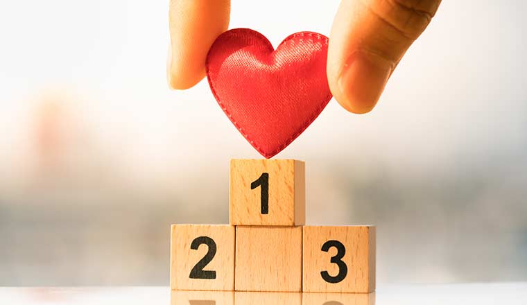 Hand holding small red heart on top of wooden podium 1, 2, 3