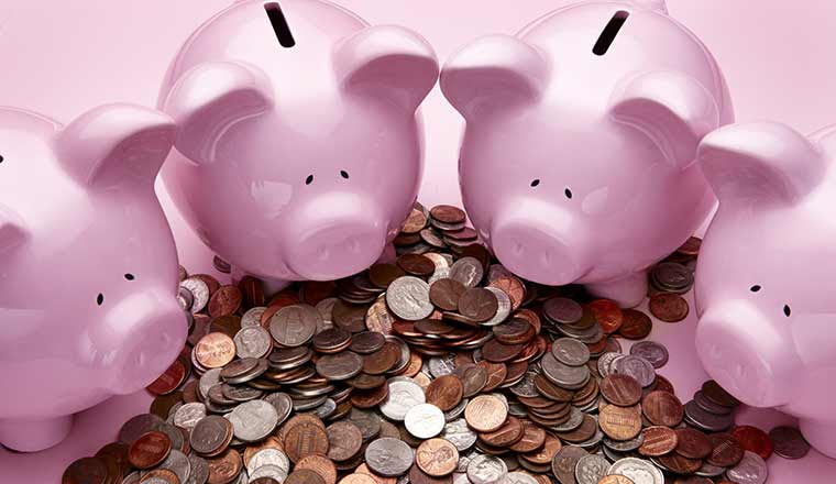 4 pink piggy banks in front of pile of coins