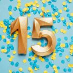 Golden number 15 on yellow and blue confetti Background
