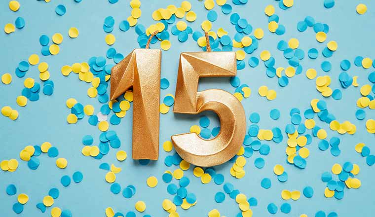 Golden number 15 on yellow and blue confetti Background