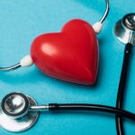Decorative red heart and black stethoscope on blue background,