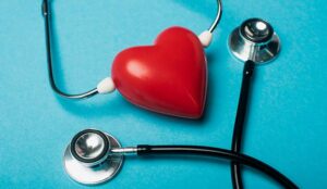 Decorative red heart and black stethoscope on blue background,