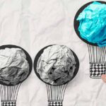 Leadership concept with hand drawn air balloons with crumpled paper ball as leader