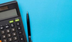 Calculator and pen on blue background