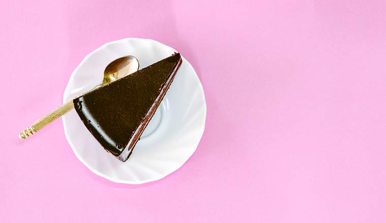 A slice of chocolate cake on pink background