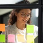 Person planning with post it notes on glass