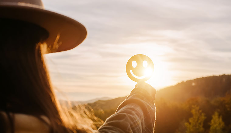 Person holding happy smile face on background amazing sunset