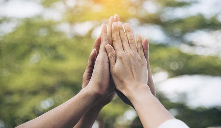 Teamwork high five as team puts hands together