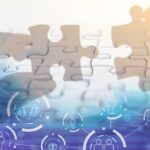 A hand holding jigsaw piece with background of teamwork people connection - technology solving staffing gaps concept