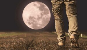 A person walking under full moon at night