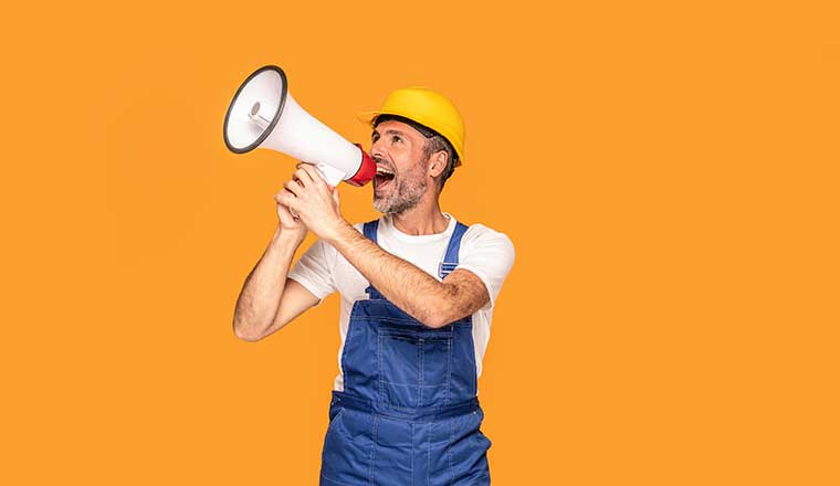 A worker shouting loud by megaphone with smile