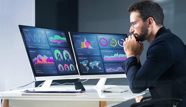 Business analytics concept with person sat at desk reviewing data