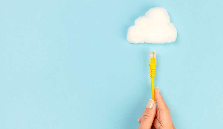 A hand holding connection cable towards the cloud on blue background