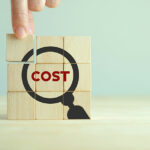 Cost management concept. With wooden cubes with the word cost and magnifying glass