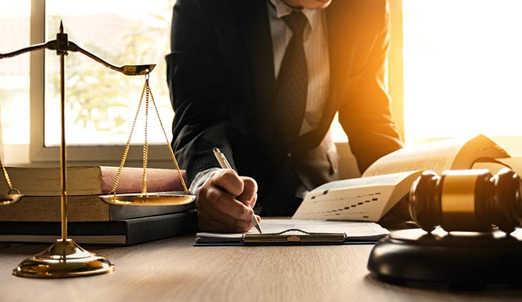 A lawyer working with contract papers and wooden gavel on table in courtroom