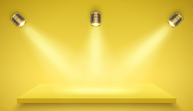 Light box with yellow platform on yellow backdrop with three spotlights. Launch and reveal concept
