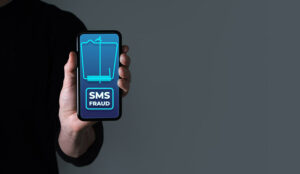 SMS Fraud Phone Concept, with Person Holding Phone with Text Message Alert on Screen