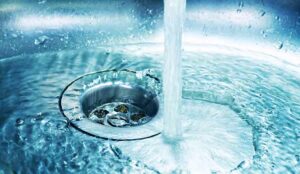 A stream of clean water flows into the stainless steel sink