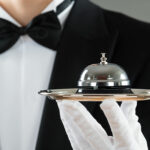 Luxury service concept with waiter holding service bell on plate