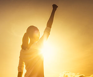 An empowered person celebrating at sunset