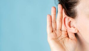 Hand is holding ear to hear better - trouble hearing concept