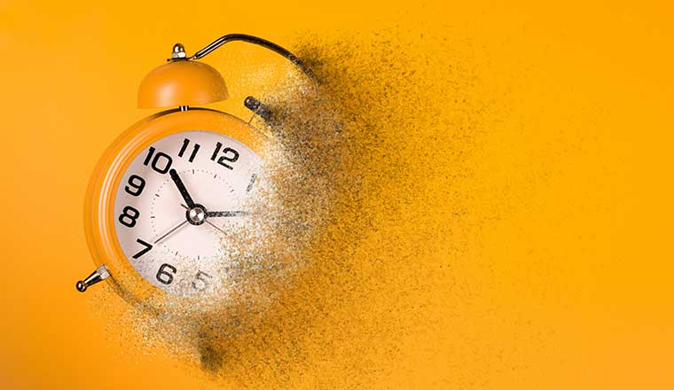 Dissolving orange alarm clock. Reducing time concept