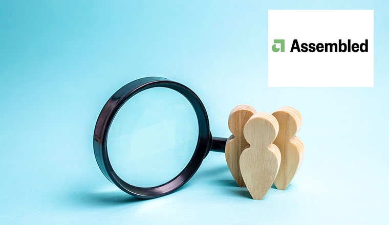 Three wooden human figure stands near a magnifying glass on a blue background.