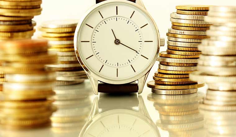 Time and money concept with clock and stack of coins