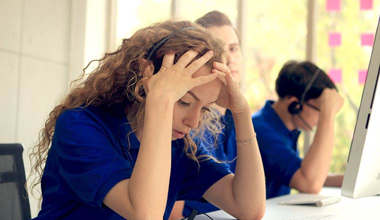 Unhappy call centre worker with head in hands