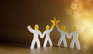 Teamwork and trust concept with paper people joined together holding gold star