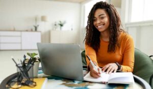 Person sat at desk with laptop and notepad - learning and training