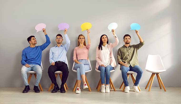 Staff surveys concept with people sitting on row of chairs holding speech bubbles