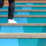 Steps to success concept with person climbing coloured stairs
