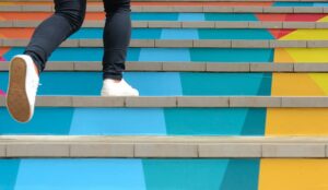 Steps to success concept with person climbing coloured stairs