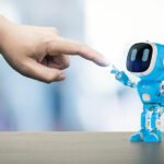 A small blue robot touching a human hand