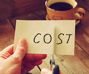 Person cutting through the word cost - reducing cost 