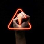 Hand writing red triangle caution exclamation warning sign
