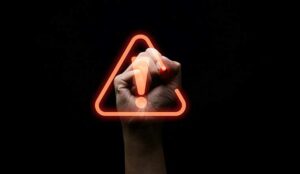 Hand writing red triangle caution exclamation warning sign