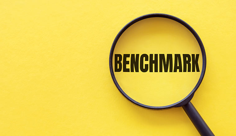 The word BENCHMARK is written on a magnifying glass on a yellow background.