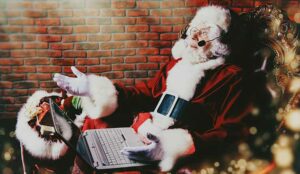 A portrait of Santa Claus is sitting in the headset with a laptop