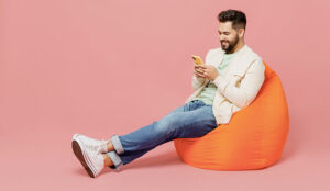 Happy person sat on bean bag looking at mobile phone