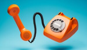 Old orange telephone with handset off.