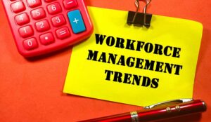Workforce Management Trends on colorful paper note with calculator and pen on red background.