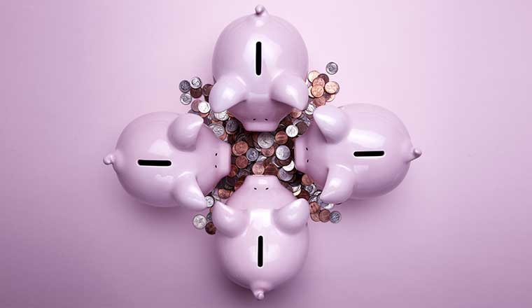 4 pink piggy banks and a pile of coins - financial services concept