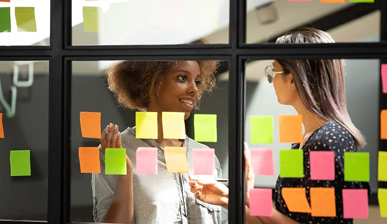 People planning with sticky notes on glass